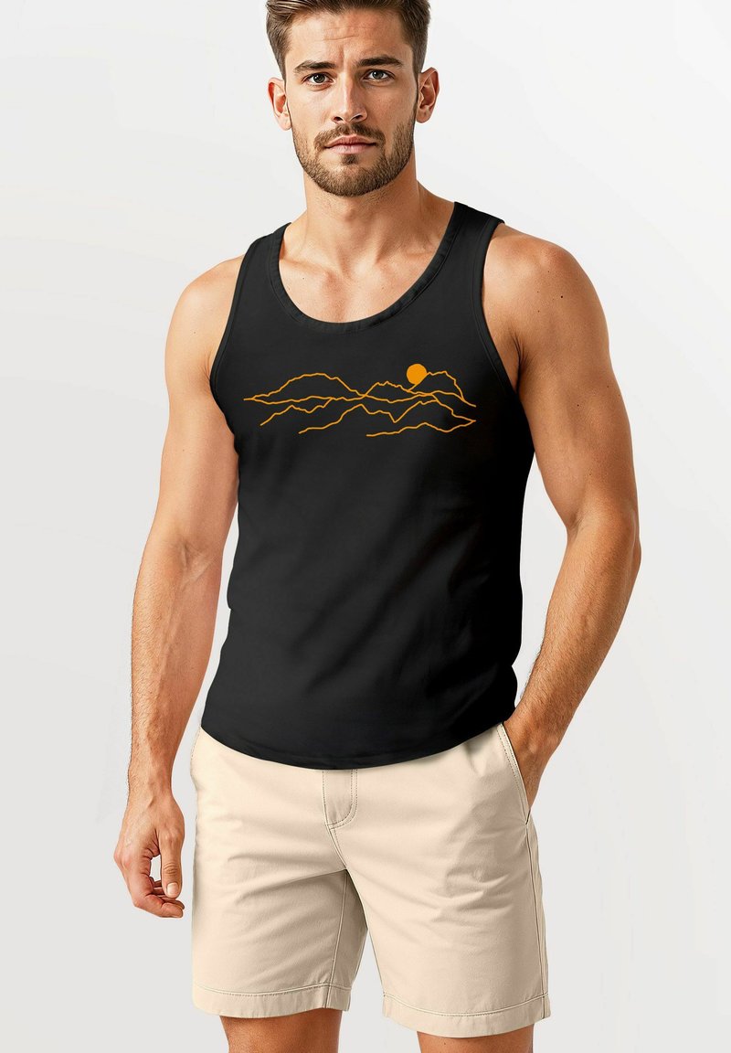 Schwarzes Tanktop mit einem Grafikmotiv von einem orangefarbenen Berg und der Sonne. Hergestellt aus einem Stoff mit glatter Textur. Modell trägt hellfarbene Shorts.