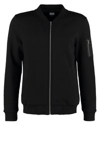 Giacca bomber nera realizzata in tessuto morbido, con zip frontale, due tasche laterali e una tasca con zip sulla manica. Polsini e orlo a coste.