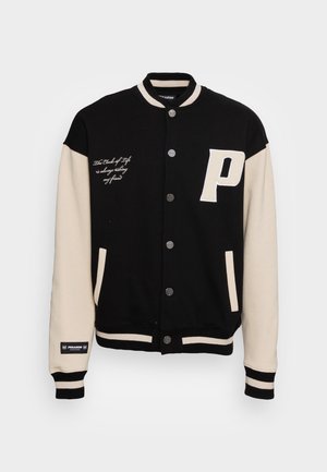 Veste universitaire noire et beige avec boutons-pression, lettre P sur la poitrine droite, texte sur la poitrine gauche, col, poignets et ourlet rayés.