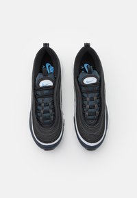 Mustat Nike-kengät, joissa on kerrostettu muotoilu, siniset yksityiskohdat, pyöreät silmukat ja valkoinen välikerros. Rakenteellinen kangas ja sileä kumipohja.