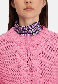 Rosa gestrickter Pullover mit einem strukturierten Kabelmuster und einem hohen, gemusterten Kragen in schwarz, rosa und lila geometrischen Formen.