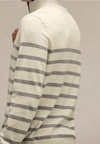 Jasny sweter w kremowym kolorze z szarymi poziomymi paskami, z ryflowym kołnierzem i mankietami. Materiał wydaje się miękki, o lekko teksturowanym wykończeniu.