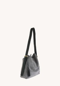 Sac à main en suede gris au design décontracté, avec une bandoulière en cuir noir ajustable, des détails en métal doré et un pompon noir.