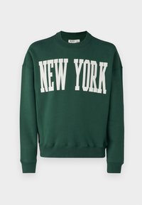 Green sweatshirt with crew neckline, featuring "NEW YORK" in large white letters across the front. Ribbed cuffs and hem. Soft texture.