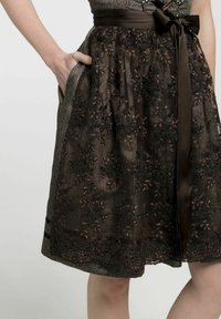 Donkerbruine jurk met bloemenborduursel, satijnen riem, zakken en een textiele stof met kantdetails.