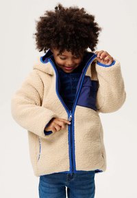 Beżowa polarowa kurtka z niebieskim kapturem i wykończeniem, zipem z przodu oraz kieszenią naszywaną w kolorze granatowym. Strukturalny materiał o przytulnym wyglądzie.