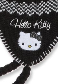 Schwarze Strickmütze mit einem weißen Hello Kitty-Graphic und einer Schleife, ausgestattet mit geflochtenen Bändern und einem Zickzack-Strickmuster am Rand.
