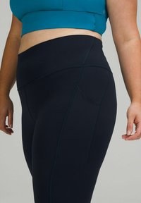 Leggings neri a vita alta con una texture liscia, dotati di una tasca laterale e dettagli di cucitura a contrasto. Adatti per l'abbigliamento sportivo.