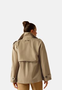 Beige trench coat with a high collar and shoulder epaulets. Features a back vent, snap buttons, and a smooth, water-resistant material.