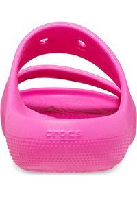Rosa gummistøvler med en teksturert overflate, sirkulære hull for ventilasjon, og en bakre stropp for støtte. "CROCS"-logo synlig.