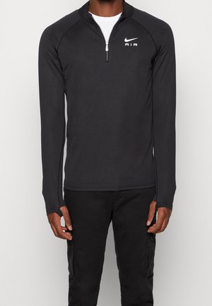 Pull-over zippé noir à manches longues, fabriqué en matériau respirant, avec un col haut et un logo Nike Air blanc sur la poitrine gauche.