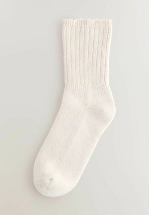 Weißer gerippter Socken mit gewelltem oberen Rand, aus weichem Material, mit glatter Textur und runder Zehenpartie.