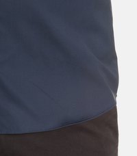 Navyblauses Hemd mit einer glatten, matten Textur; mit abgerundetem Saum und subtilen Nähten, kombiniert mit schwarzen Hosen.