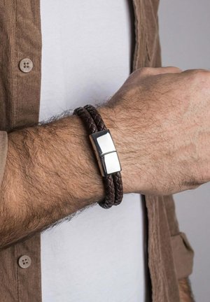 Male wrist wearing a double-wrap dark brown braided leather bracelet with a shiny silver rectangular clasp.