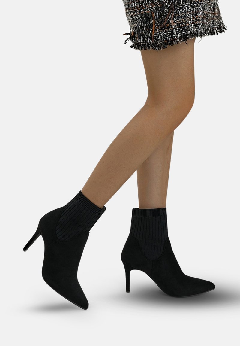 Stivaletti neri con tacco alto realizzati in suede, con accenti a coste neri in cima, punta affilata e tacco a stiletto.