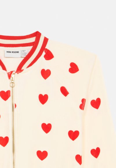 Chaqueta cremoso con cremallera y estampado de corazones rojos, con cuello de canalé a rayas rojas y blancas de Mini Rodini, talla 9-11 años.