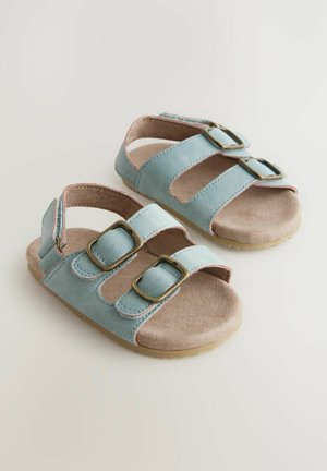 Hellblaue Wildledersandalen mit zwei verstellbaren Schnallen, hellbraunen Innensohlen, offenem Design und strukturierten Gummisohlen.