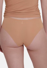 Beige naadloze high-waisted onderbroeken met een gladde, rekbare textuur. Minimale branding op de tailleband gedrukt. Geen zichtbare naden.
