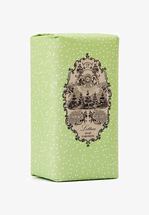 Grüne Seifenverpackung mit weißen Polka-Dots und einem Vintage-Etikett, das schwarze Grafiken, Text und einen verzierten Rand zeigt.