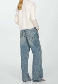 Light beige cropped sweater paired with oversized light blue denim jeans, featuring a high waist and standard back pockets.