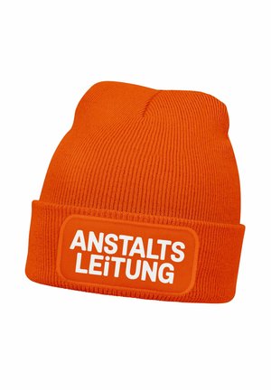 Orange gestrickte Mütze mit einer gerippten Textur und einem rechteckigen Aufnäher mit dem Wort "ANSTALTSLEITUNG" in fetten weißen Buchstaben.