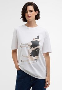 T-shirt de algodão branca com uma grande estampa de uma vaca em preto e branco, corte relaxado, mangas curtas e decote redondo.