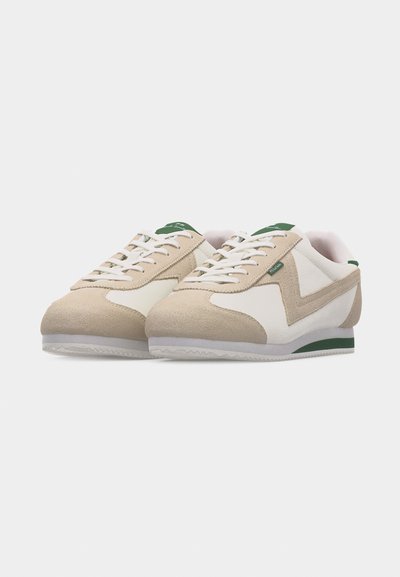 Paire de baskets basses beige et blanches avec des lacets blancs et des accents verts sur la languette et le talon, présentées sur un fond blanc.
