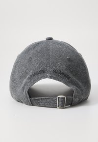 Grå baseballcap med strukturert stoff, justerbar metallstropp bak, og subtil merking langs siden.