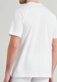 T-shirt en coton blanc à manches courtes et col rond, présentant une texture lisse et un design simple et moderne sans embellissements.