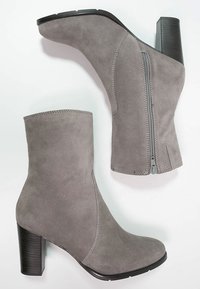 Botas de tobillo de ante gris con un diseño cónico, cremallera lateral y un tacón cuadrado negro. Textura suave con detalles de costura decorativa.