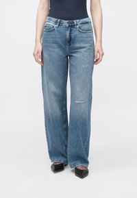 Světle modré džíny s širokými nohavicemi z denimu, s vybledlou texturou a opranými detaily, s kapsami a zapínáním na knoflíky vpředu.