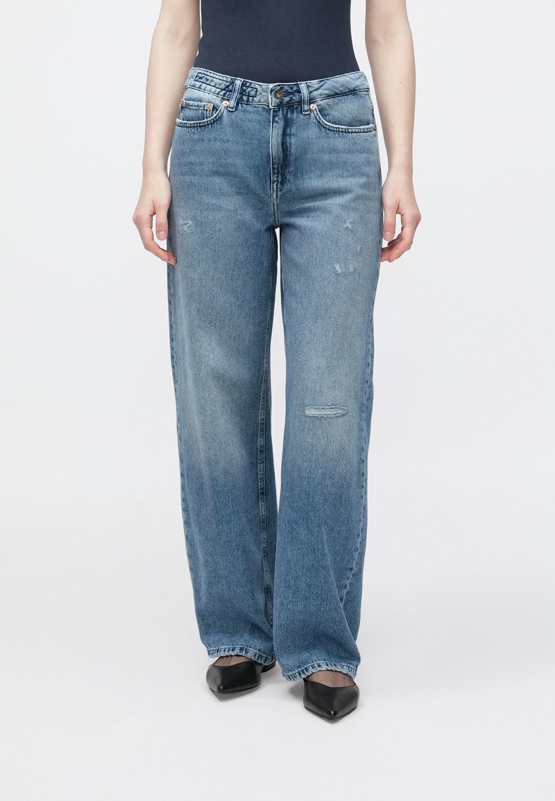 Světle modré džíny s širokými nohavicemi z denimu, s vybledlou texturou a opranými detaily, s kapsami a zapínán�ím na knoflíky vpředu.