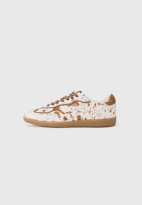White sneakers with brown splatter pattern, featuring beige laces, rounded toe, and rubber sole. Textured accents on sides and back.