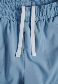 Ljusblå träningsshorts med elastisk midja och vit dragsko, som har ett mjukt tyg och diskreta sömdetaljer.