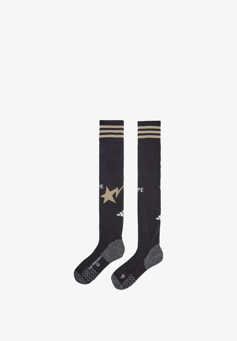 Calze nere lunghe fino al ginocchio con strisce dorate in alto, decorate con un design di stelle dorate e suole grigie texture.