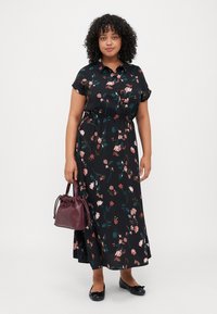 Black floral maxi dress with short sleeves, featuring pink and green flowers. Worn with a burgundy handbag and black flats. Smooth fabric, relaxed fit.