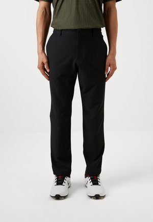 Black pants with a smooth texture and regular fit, featuring a front pocket and belt loops, worn with white golf shoes.