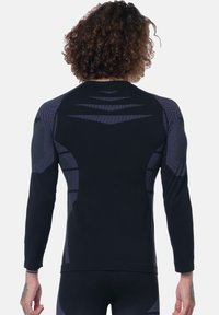 Black long-sleeve athletic shirt featuring textured mesh panels in a lighter shade, with a fitted silhouette and minimal seam details.