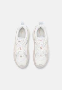 Hvide sneakers med en polstret design, mesh og glat læder materialer, lyse beige accenter og en tekstureret gummisål. Inkluderer et logo.