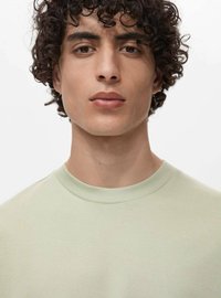 Světle zelené bavlněné tričko s kulatým výstřihem a krátkými rukávy. Tkanina vypadá hladce s jemnou strukturou.