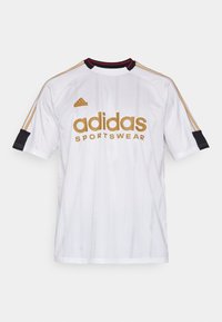 Vit Adidas sporttröja med guldlogotyp och ränder. Har svarta detaljer på ärmarna. Tillverkad av lättviktsmaterial med vertikala linjer.