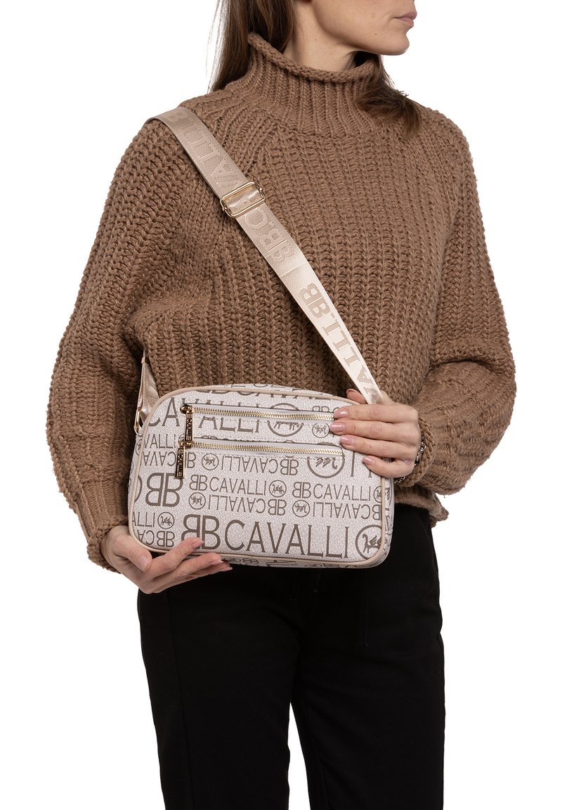 Borsa a tracolla beige con logo in rilievo, chiusura con zip e tracolla regolabile. Realizzata in materiale testurizzato con un accento liscio.