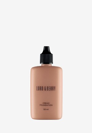 Fond de teint crémeux dans un flacon beige avec un capuchon à vis noir. Présente un texte noir pour le nom de la marque et les détails du produit. Contient 50 ml.