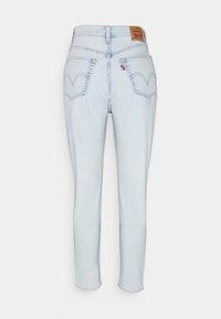 Jeans en denim bleu clair avec une taille haute, poches arrière nettes et une étiquette en cuir de marque au niveau de la taille ; coupe slim qui se resserre vers les chevilles.