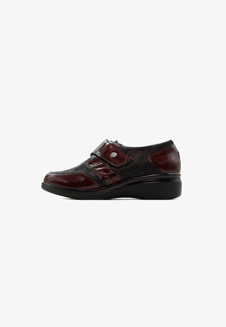 Zapato de mujer de tacón bajo con tejido negro y paneles de charol rojo oscuro, con una correa lateral y detalle de botón metálico.