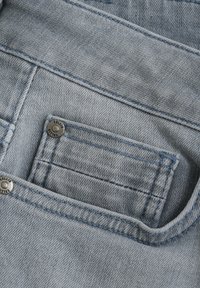 Ljusblå denimficka med silverfärgade knappar, kontrasterande sömmar och en texturerad tygfinish, med en ren kantdesign.
