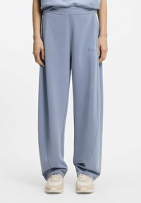 Light blue sweatpants made of soft fabric with a wide leg design, featuring an elastic waistband and discreet logo detail.