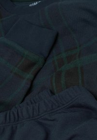 Námořnický modrý pulovr se vzorem, s zeleným a černým károvaným vzorem, se žebrovanými manžetami. Koordinující námořnické modré tepláky s elastickým pasem.