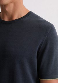 Ciemnogranatowy t-shirt z krótkim rękawem wykonany z teksturowanej tkaniny, z okrągłym dekoltem i subtelnym zielonym akcentem na brzegach rękawów.