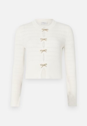 Fehér kötött cropped kardigán, hosszú ujjal, texturált mintával és öt arany masni záróelemmel az elején.